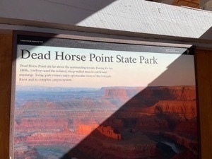 Wayside interpretive sign for Dead Horse Point State Park with sunbeaum illuminating the title text that says Dead Horse Point State Park