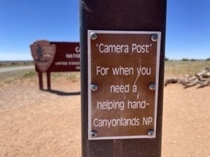 SIgn announcing post with small platform to be used for selfies in front of the main sign for for Canyonlands National Park. Sign says 