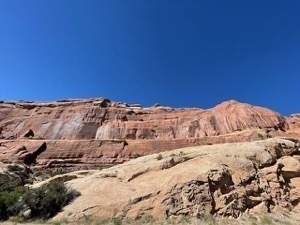 Wide angle view of giant orange hillside with striated rocks and deep blue sky in Arches National Park near Moab Utah